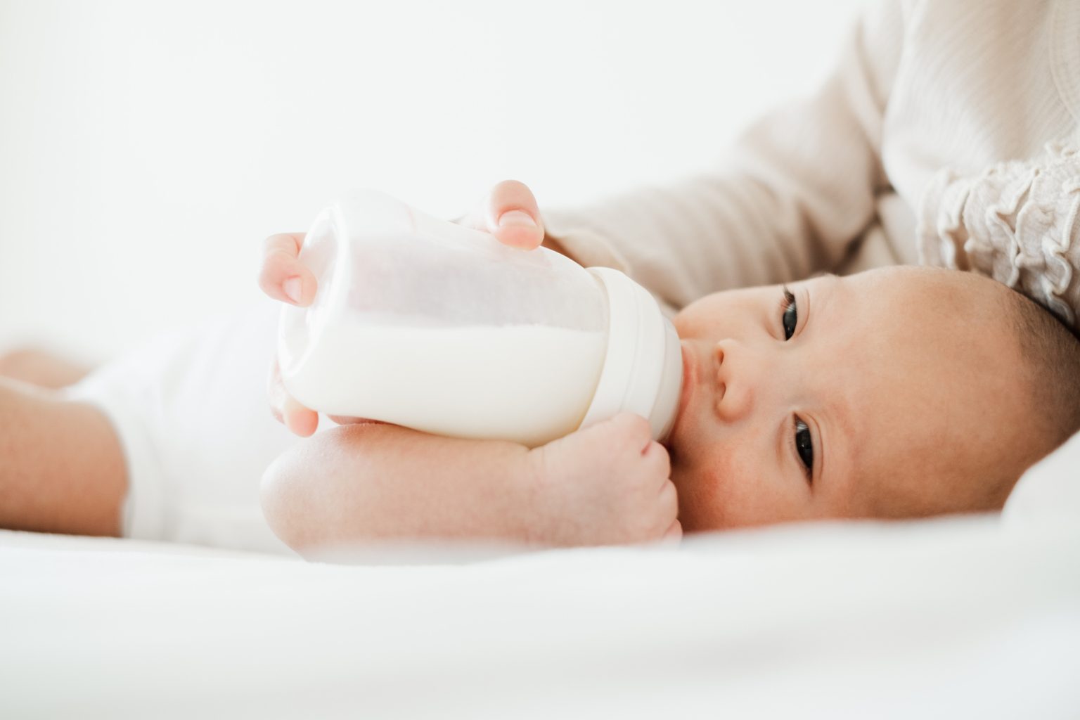 Малыш кушает из бутылочки молоко дома перед сном
